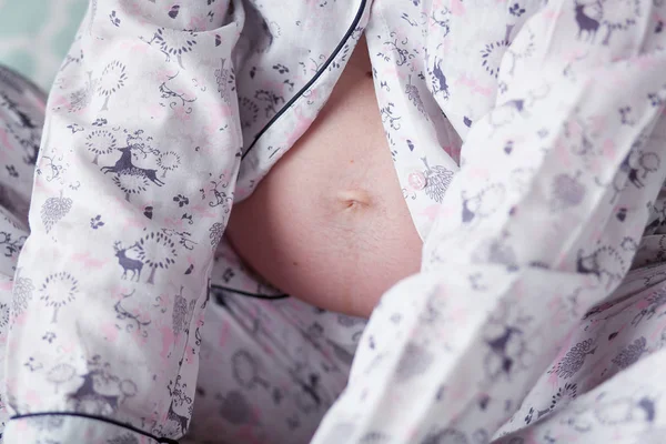 Imagem de close-up de uma barriga de mulher grávida em pijama — Fotografia de Stock