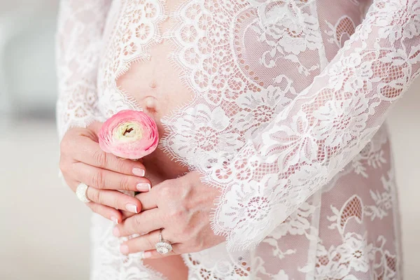 Mulher grávida segurando flor de ranúnculo acima da barriga — Fotografia de Stock