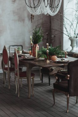 Yüksek tavan, vintage koltuklar, boş gri beton duvar, ahşap zemin, yemekler, yemek masası ile modern loft yemek odası çiçekler ve mumlar. Rahat iç fotoğrafı alay