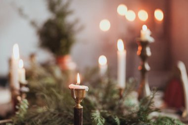 Yanan mumlar ve çam dalları ile şenlikli Noel masa dekorasyon aranjmanı