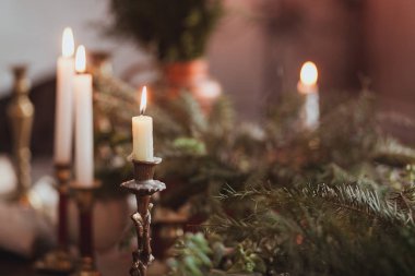 Yanan mumlar ve çam dalları ile şenlikli Noel masa dekorasyon aranjmanı