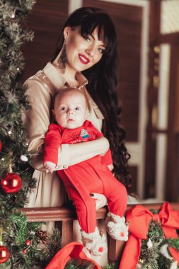 Anne ve garland, toplar, kırmızı meyveler ile dekore edilmiş Noel ağacı arka plan üzerinde yeni doğan oğlu portresi