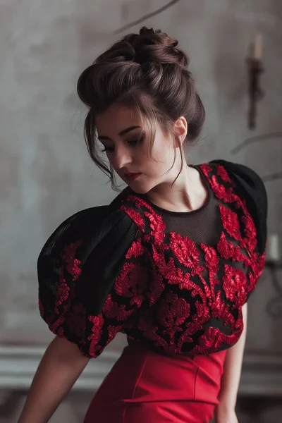 Retrato de la mujer en vestido rojo en el interior del loft con pared de hormigón en el fondo. Sombra en la cara — Foto de Stock