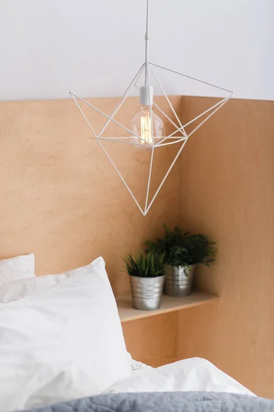 Loft stil geometriska vitt taklampa med ljus trä bakgrund och en edison glödlampa. Grön växt i potten i hörnet. Inomhus. — Stockfoto