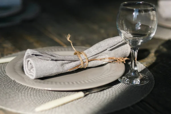 Configuración de la mesa. Un plato gris. Cuchillo y tenedor. Una copa de vino pasada de moda. Servilleta rústica. Mesa de madera. Enfoque selectivo — Foto de Stock