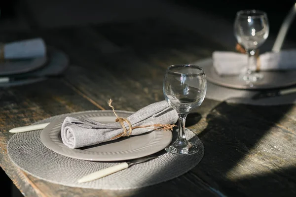 Configuración de la mesa. Un par de platos grises vacíos. Cuchillo y tenedor. Copas de vino a la antigua. Servilleta rústica. Mesa de madera. Enfoque selectivo — Foto de Stock