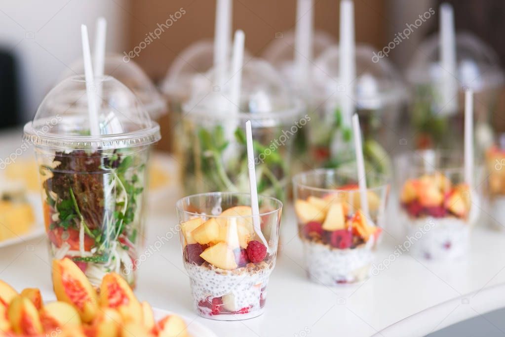 Mini desserts and healthy vegetable microgreen salads in plastic cups canaps. Catering served table