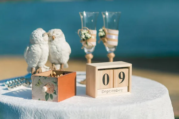 Tavolo da sposa decorato con calendario cubo in legno, bicchieri di champagne, gufi in ceramica . — Foto Stock