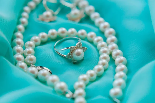 Collar de perlas y anillo sobre fondo satinado de lujo — Foto de Stock