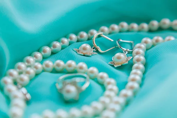 Collar de perlas, pendientes y anillo sobre fondo satinado de lujo — Foto de Stock
