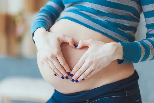 Concepto de expectativa - primer plano de la mujer embarazada feliz haciendo signo de la mano en forma de corazón en su barriga desnuda — Foto de Stock