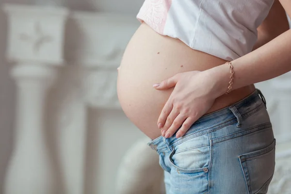 Mujer embarazada de siete meses en jeans. Vista frontal de cerca — Foto de Stock