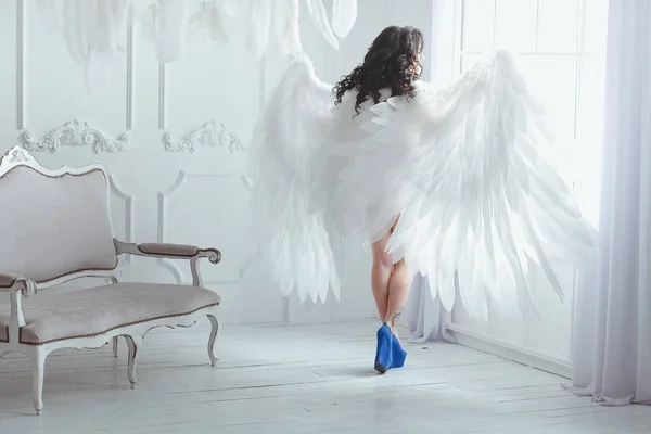 Hermosa joven morena embarazada con grandes alas de ángel en estudio blanco. La mujer volvió a la cámara buscando maravillarse . — Foto de Stock