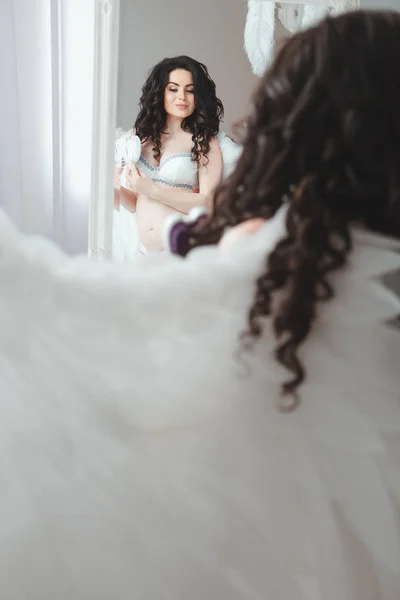 Chica joven sensual y hermosa en lencería nupcial y alas de ángel mirando en el espejo — Foto de Stock