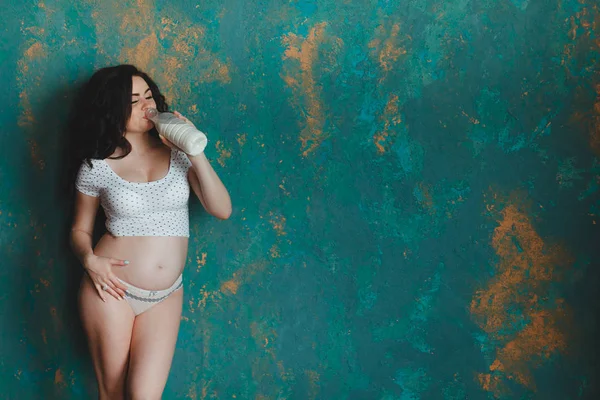 Mulher grávida a beber leite. Isolado no fundo da parede rústica — Fotografia de Stock