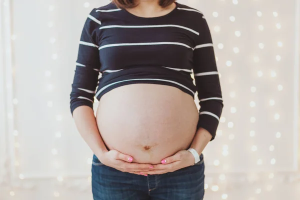 Nahaufnahme von schwangeren Frauen großen behaarten Bauch auf hellen Bokeh-Lichtern Hintergrund — Stockfoto