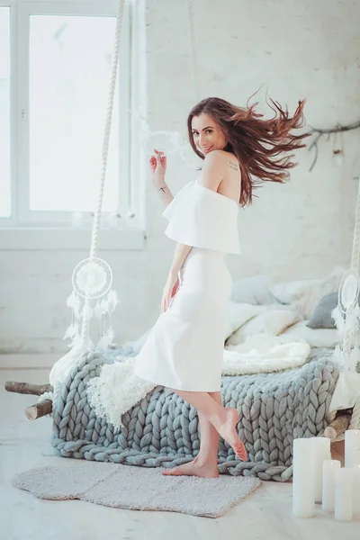 Uma mulher sexy de pé na cama com dreamcatcher, loft interior minimalista — Fotografia de Stock