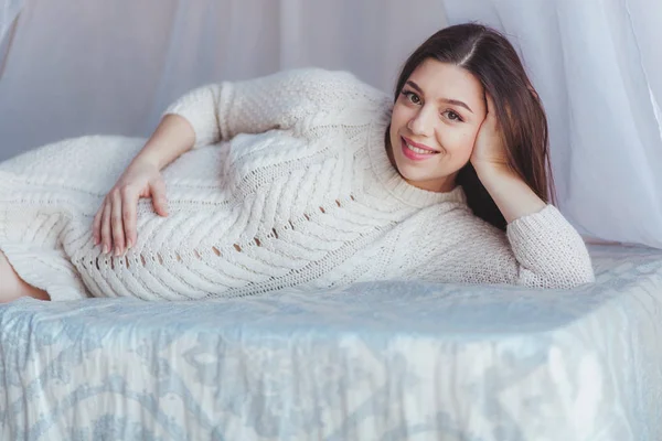 Charmante schwangere Frau liegt zu Hause auf einem Bett mit Baldachin — Stockfoto