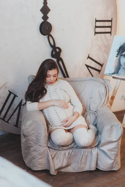Mulher grávida olhando para a barriga com um grande relógio no fundo. Conceito de espera — Fotografia de Stock