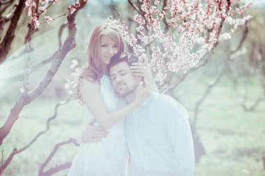 Aşk çift çiçek açan elma bahçesinde sarılma beyaz bokeh etkisi.