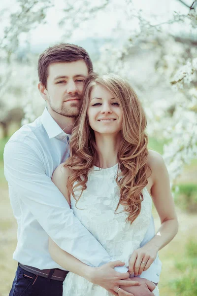 Açık mutlu çift çiçek açan parkta poz aşık. Genç erkek ve kız açık eğleniyor