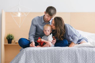 Mutlu bir aile. Anne ve baba ile bebek yatak odasında. Aile giyim bak. Anne öpücük oğlu.