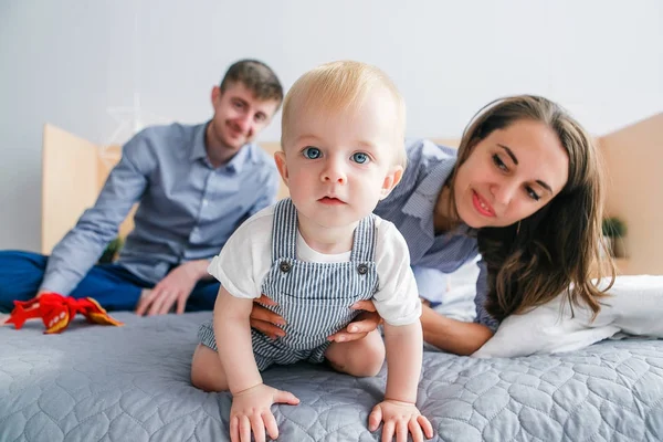 Jovem família brincar na cama em casa, bebê olhando para a câmera. Imagem de close-up — Fotografia de Stock