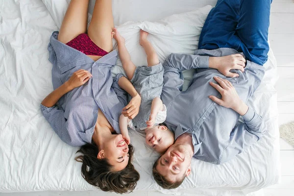 Famiglia sdraiata a testa in giù sul letto in pigiama insieme. Look familiare . — Foto Stock