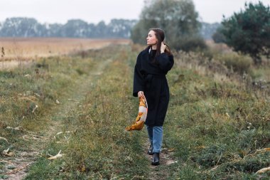 Coutryside yolu üzerinde duran genç kadın. Sonbahar, bulutlu hava
