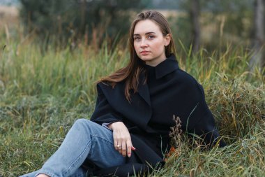 Esmer kadın koyu yeşil sonbahar çim üzerinde yalan. Rahat moda stil