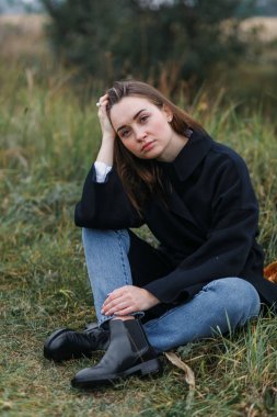 Esmer kadın koyu yeşil sonbahar çim üzerinde yalan. Rahat moda stil