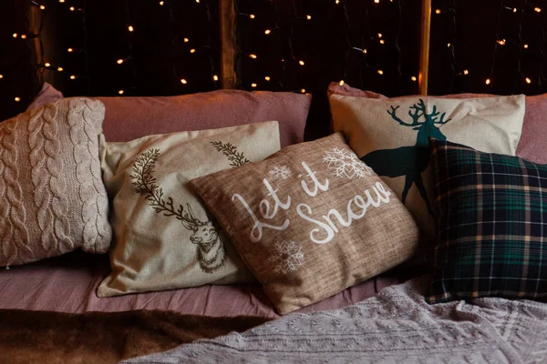 Jul Mys kväll, kuddar på en soffa med garland ljus bokeh bakgrund. Låt det snö text på kudde — Stockfoto