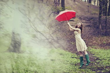 Bir kadın ile onun kırmızı noktalı şemsiye ormandaki üflenir. Mary Poppins kavramı