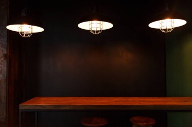 Çatı katı iç beton tasarım, ahşap masa. Karanlıkta üç ışık kolye