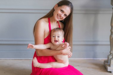Genç anne sarılma mutlu gülümseyen bebek katta oturan