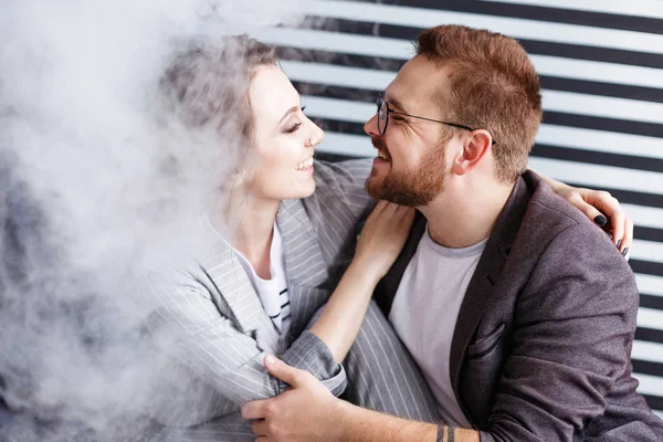 Hipster uomo barba e donna sexy stanno vaporizzando. Sparatoria in studio. Sfondo bianco e nero . — Foto Stock