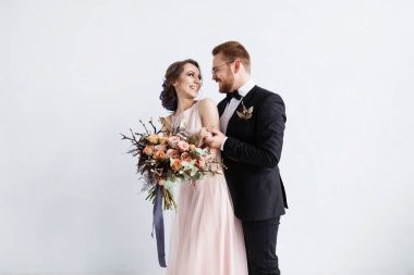 Mutlu yeni evliler tam uzunlukta portresi. buket ile. Beyaz duvar arka planda izole izole