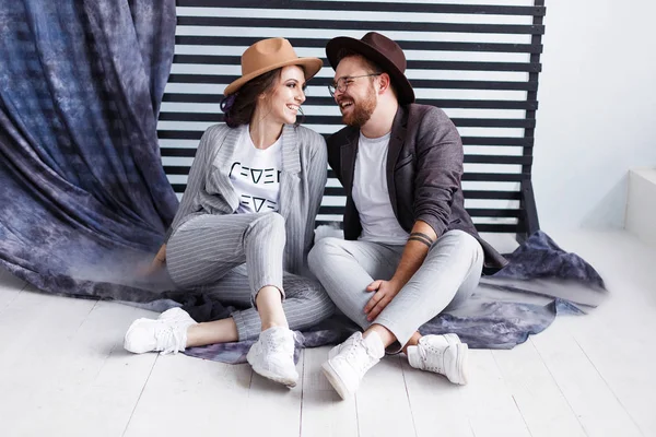 Portrait of a beautiful young happy smiling couple. Modern hipster man and woman in studio with copyspace — Stock Photo, Image