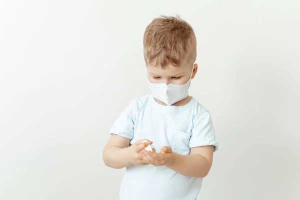 Menino na máscara médica usando garrafa de desinfetante — Fotografia de Stock