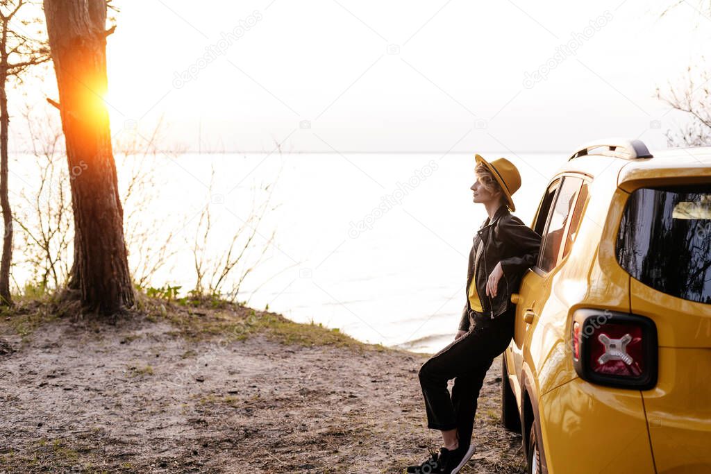 Young Woman Lean against Car at Sea Shore Sunset