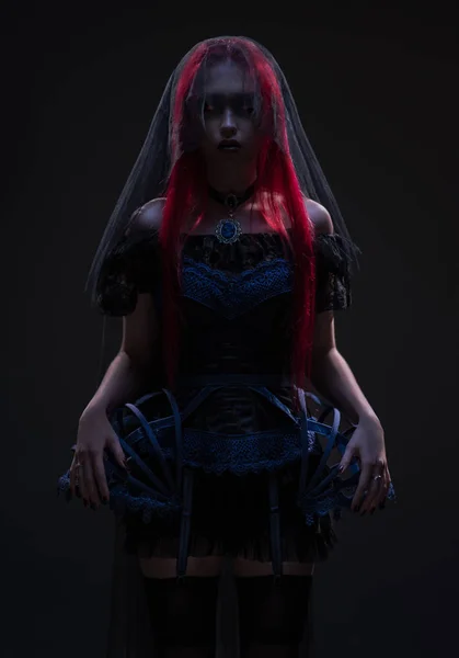 红色头发和黑色面纱的妇女在黑暗的背景下摆出 — 图库照片