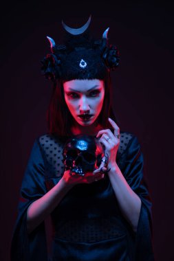 Gotik tarzda siyah elbiseli genç bir kadın kafatasıyla poz veriyor.