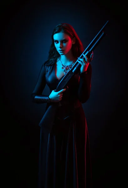 一个拿着枪在演播室摆姿势的年轻女人 图库图片