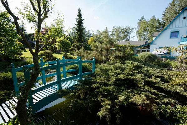 Kleine groene voetgangersbrug over een tuin vijver van Lente — Stockfoto