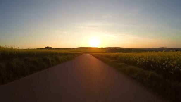 Ηλιοβασίλεμα με το αυτοκίνητο στο δρόμο αγροτικής υπαίθρου την άνοιξη — Αρχείο Βίντεο