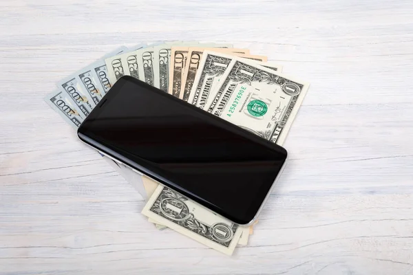 Mobilní telefon a americký dolar peníze na bílém — Stock fotografie