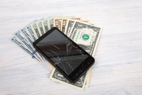 Teléfono celular agrietado y dinero estadounidense en blanco —  Fotos de Stock