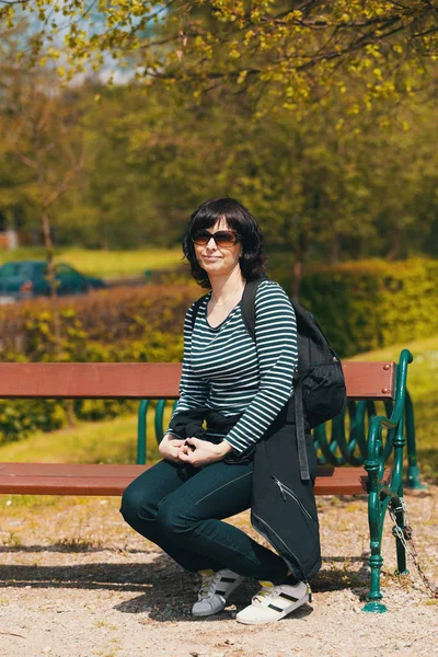 Уставшая женщина среднего возраста отдыхает на скамейке — стоковое фото