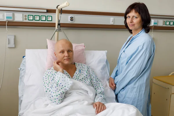 化学療法後の髪のない女性患者は 病院のベッドに横たわって悲しみと憂うつな心配感 友人が彼女を喜ばせに来た 医療と臨床的注目の概念 — ストック写真