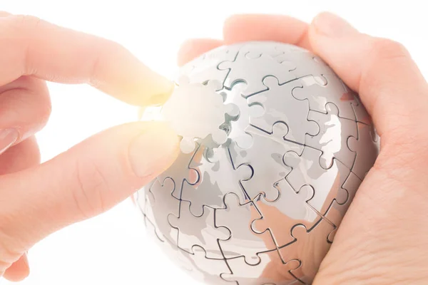 Businessconcept met een hand gebouw puzzel globe op wit, ruimte voor berichten — Stockfoto